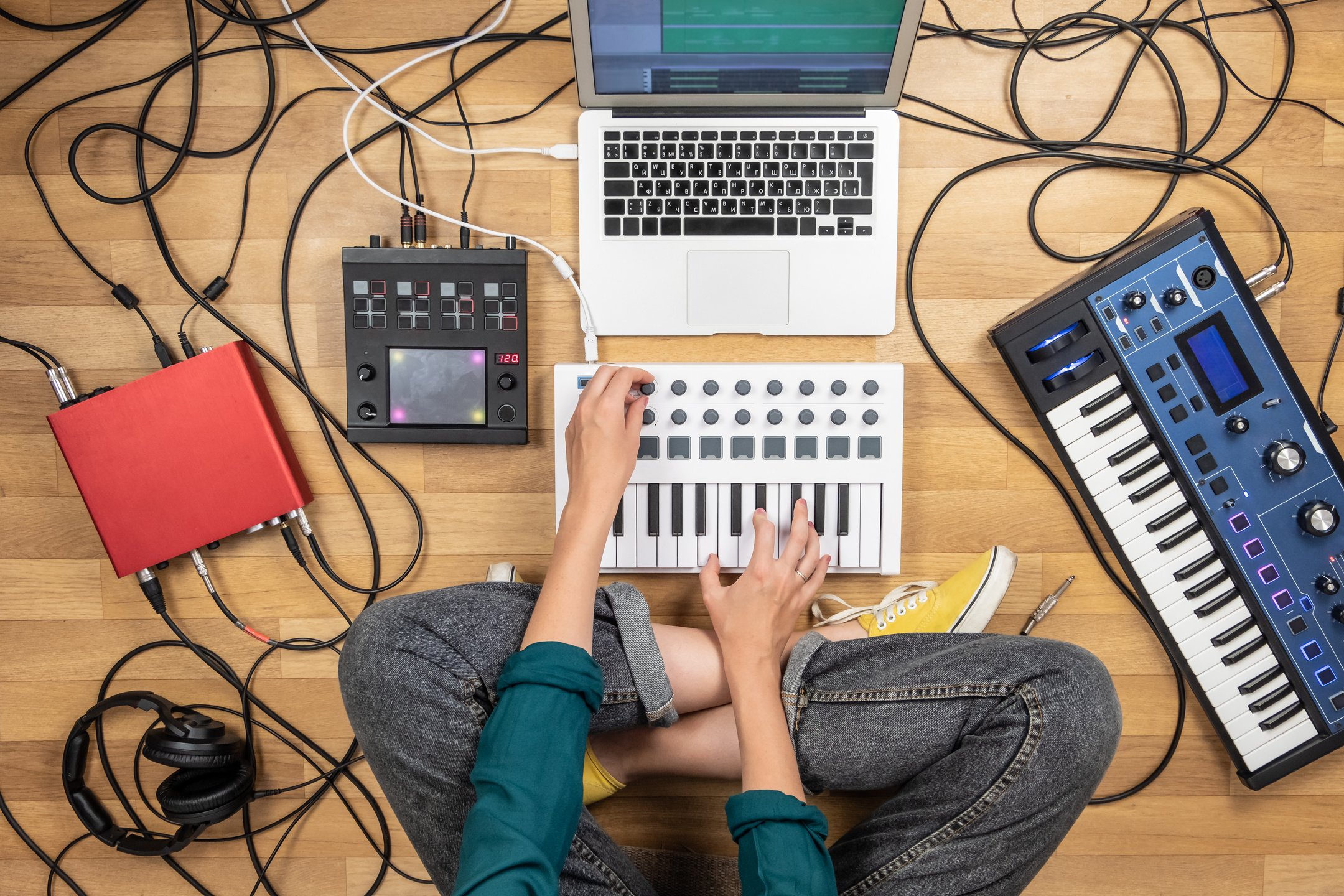 Woman making electronic music on laptop computer and digital instruments.